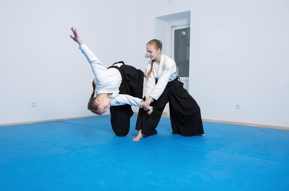 Two girls in black hakama practice Aikido on martial arts training