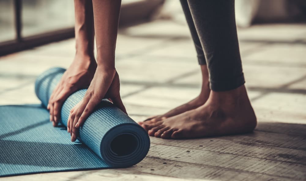 person rolling yoga mat