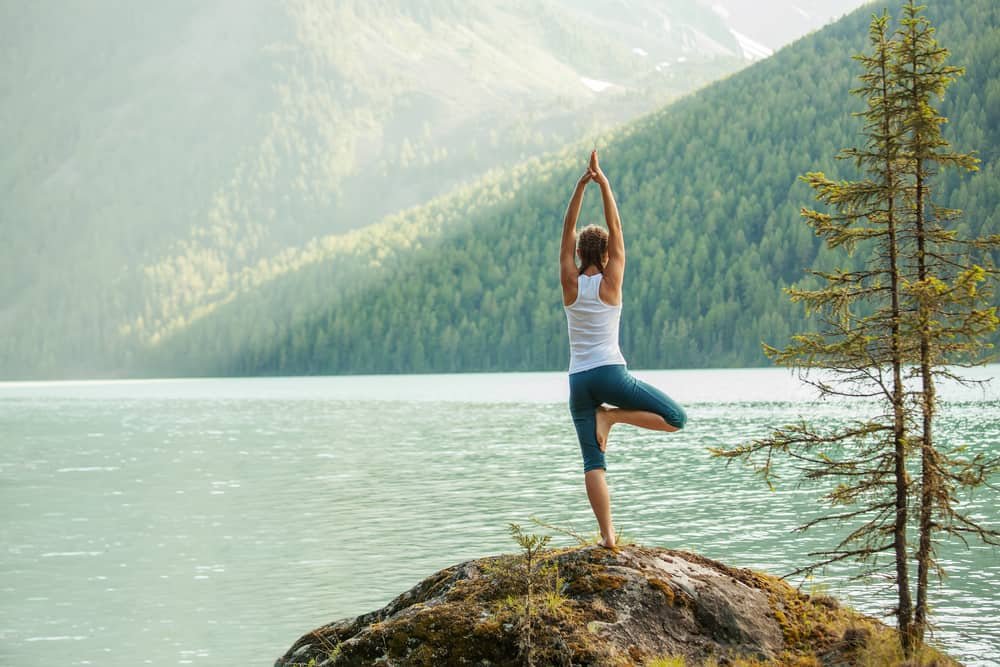 woman is practicing yoga at mountain lake